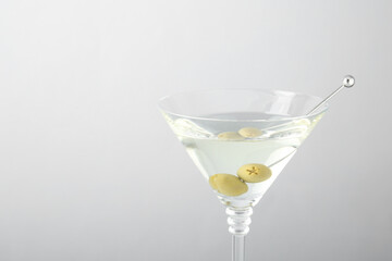 Martini cocktail with olives in glass on light grey background, closeup. Space for text