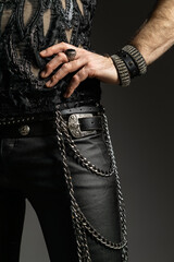 A bold and stylish rock-inspired outfit featuring black leather pants, studded belts, layered...