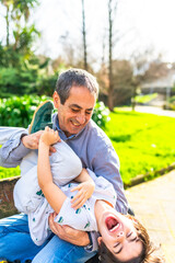 Grandfather tickling grandson in the park, authentic family moments