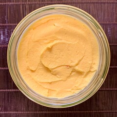 This creamy mango sorbet is presented in a clear glass jar, showcasing its vibrant yellow color. The dessert looks smooth, inviting a taste of tropical sweetness
