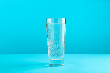 Soda water in glass on light blue background