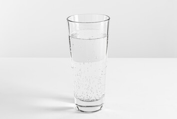 Refreshing soda water in glass on white table against light background