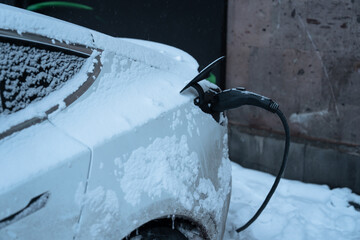Electric Car Charging in Winter with Snow and Cold Weather Conditions.