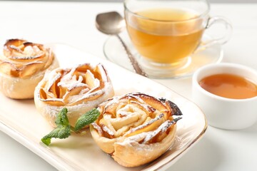 Freshly baked apple roses with mint, honey and tea on white table, closeup