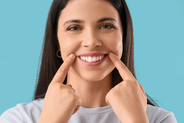 Young woman with healthy teeth smiling on blue background, closeup