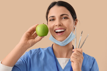 Female dentist with apple and tools on beige background, closeup
