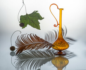 Beautiful glass jug and dried palm leaf on a light background.