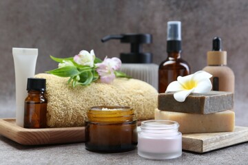 Different body care products and flowers on grey table