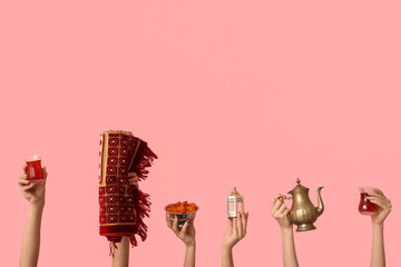 Female hands with Turkish tea, prayer rug, dried apricots and lantern on pink background