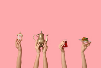Female hands with Turkish tea, baklava and lantern on pink background