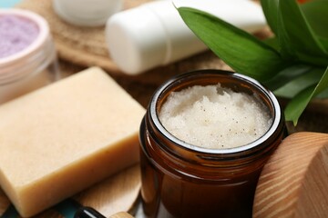 Different body care products and green leaves on table, closeup