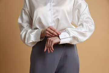 Beautiful woman in stylish outfit on beige background, closeup