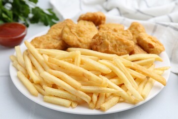 Tasty chicken nuggets and french fries with sauce on white tiled table, closeup
