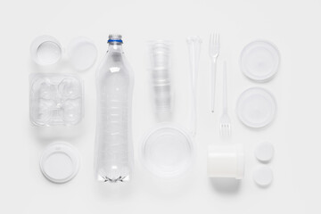 Plastic bottle with forks, cups, containers, caps and cable ties on white background