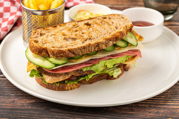 Club sandwich with lettuce, cheese, cucumber, and deli meats on a plate