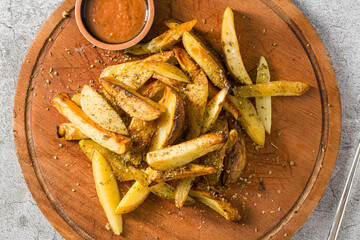Spicy French fries with hot sauce on a cutting board