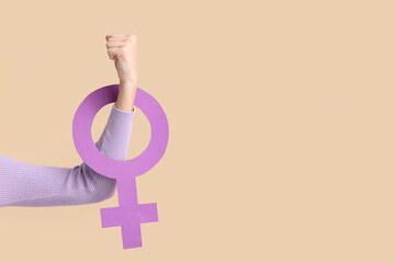 Young woman with female symbol showing muscles on beige background. Women's history month