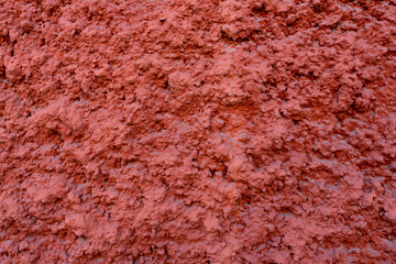 Crépi rouge taloché et texturé sur un mur de construction