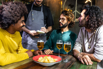 Waiter taking order from group of friends having drinks in a restaurant