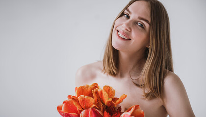 Fototapeta premium Red-haired girl, natural beauty with a bouquet of tulips on a light background, minimalism, femininity
