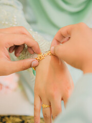 The groom put the wedding bracelet to the bride during solemnization ceremony. Family and happiness concept.