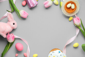 Frame made of Easter eggs, tulip flowers and decorative nest and bunny on grey background