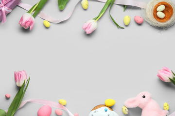 Frame made of Easter eggs, tulip flowers and decorative nest and bunny on grey background
