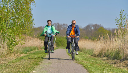 Naklejka premium happy mature couple riding a bike in springtime outdoor in nature