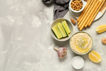 Bowl of delicious hummus with lemon, Italian Grissini, cucumber and chickpeas on light grunge...