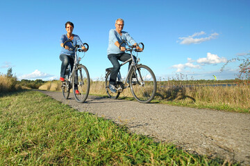 Naklejka premium man and woman riding bikes in spring season in nature
