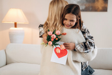 Hugs, celebrating mother's day. Woman and her daughter are together in domestic room