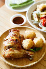 Grilled chicken with fried white rice on wooden tray.