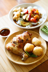 Grilled chicken with fried white rice on wooden tray.