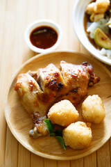 Grilled chicken with fried white rice on wooden tray.