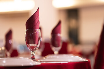 Table set up with a maroon folded napkin placed in a wine glass.