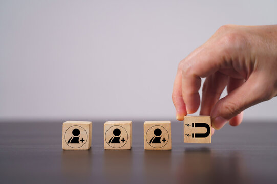 Customer retention concept. Inbound marketing strategy. Attracting potential customers. Hand puts wooden cubes with magnet attracts customer icons on beautiful grey background and copy space. Loyalty 