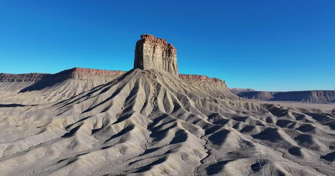 An unworldly, wide-angle drone shot, approaching an isolated, monolithic rock pillar known as Chimney Rock, or Jackson Butte, located in the Mesa Verde Region, in the southwestern corner of Colorado