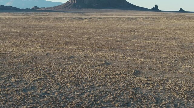 A low to the ground, slow-rising 70mm drone shot of the sacred &ldquo;Ship Rock&rdquo;, a massive, monolithic monadnock towering above the high-desert plain of the Navajo Nation, in New Mexico, United States.
