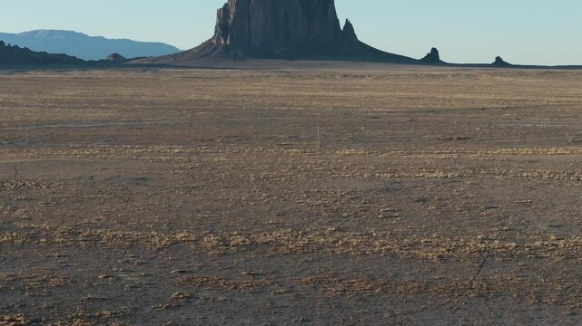 A low to the ground, slow-rising 70mm drone shot of the sacred &ldquo;Ship Rock&rdquo;, a massive, monolithic monadnock towering above the high-desert plain of the Navajo Nation, in New Mexico, United States.