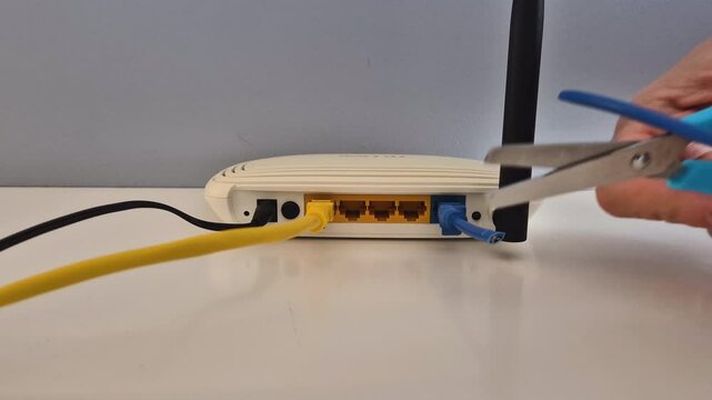 Scissors cut blue internet cable connected to the WAN portal of a router