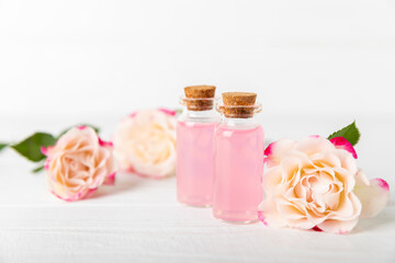 Rose essential oil on a textured background.Roses and a bottle of rose perfumed water.Aromatherapy treatment. Beauty concept. Spa procedure.Natural organic oil.Anti-stress,detox relax.Place for text