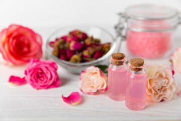 Rose essential oil on a textured background.Roses and a bottle of rose perfumed water.Aromatherapy treatment. Beauty concept. Spa procedure.Natural organic oil.Anti-stress,detox relax.Place for text