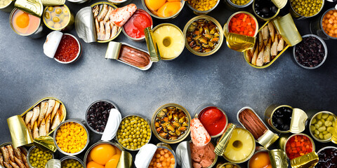 Food background in tin cans. Canned vegetables, beans, fish and fruits on a stone background. Food...