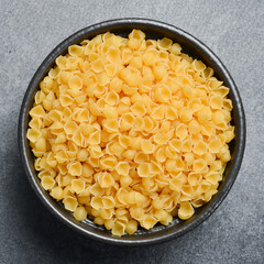 Close up. Bowl of raw Italian pasta. Top view. On a gray stone background.