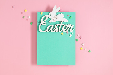Easter greeting card. Top view of blank paper blue paper for text with Easter themed decoration on pink background.