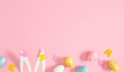 Bright Easter eggs with patterns and rabbit ears on a pastel pink background. Easter composition. Top view.
