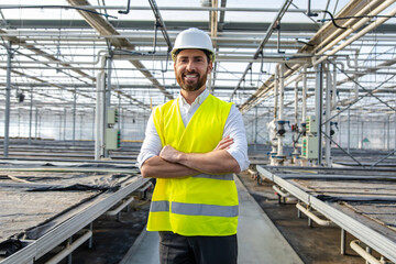 Young determined engineer in yellow protective vest in a greenhouse construction site
