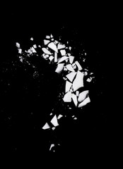 Debris or fragments of white porcelain isolated on black. White glass explosion on black background.