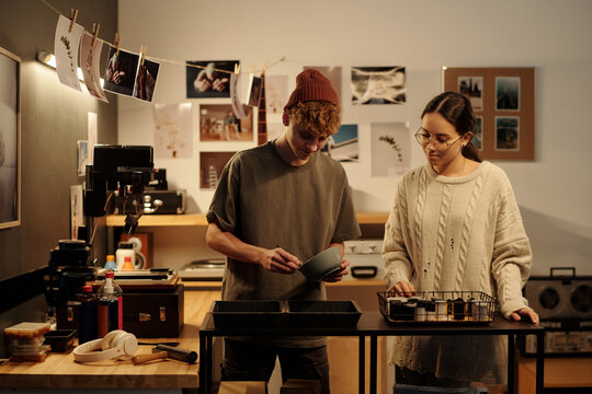 Waist up portrait of teenage boy and girl working together developing photo prints in studio young photographers in creative studio copy space