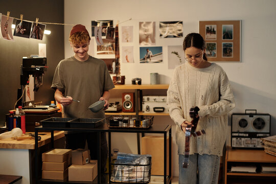 Portrait of two young photographers collaborating on creative process in studio and developing photo film together
